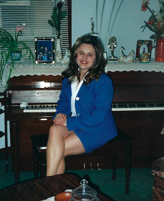 A photo of a woman sitting by the piano.