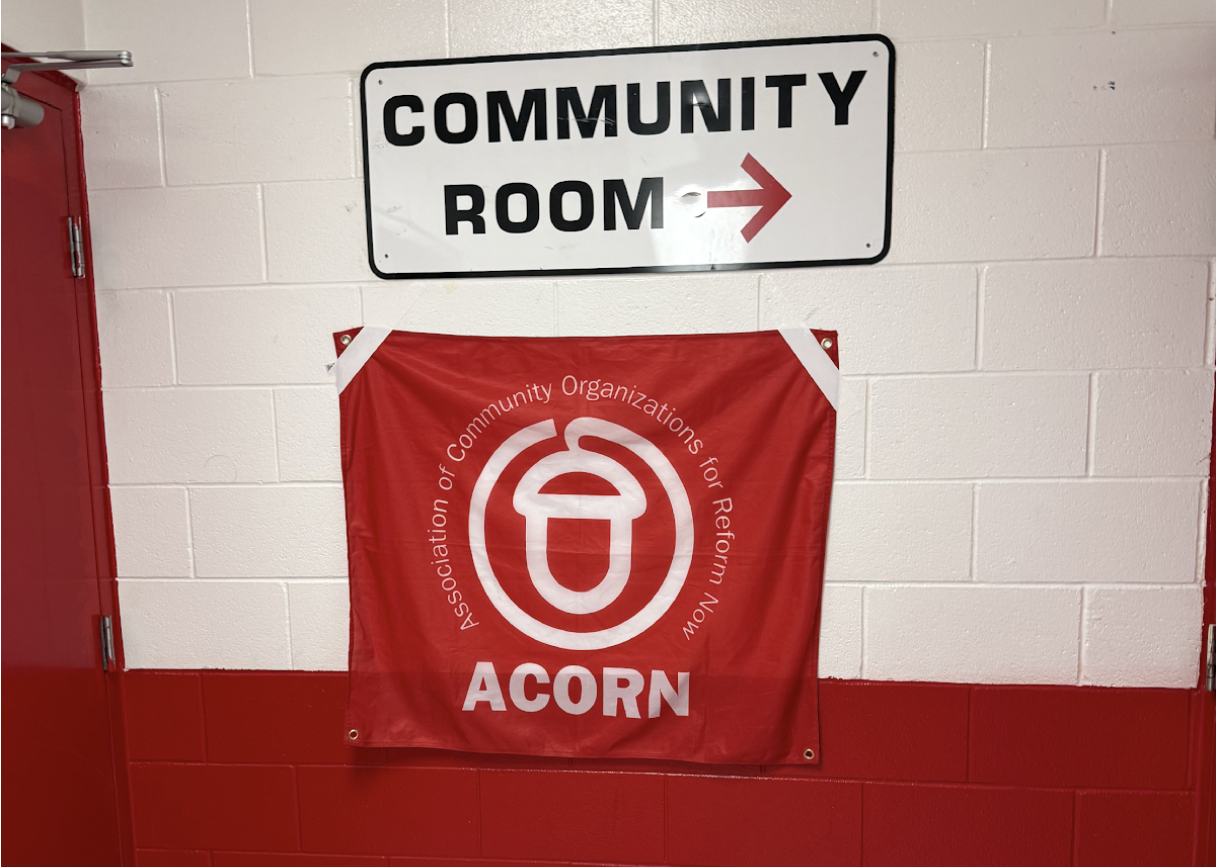 A white metal signed reading "Community Room" with an arrow pointing right. Underneath it, a fabric flag reading "ACORN Association of Community Organizations for Reform Now"