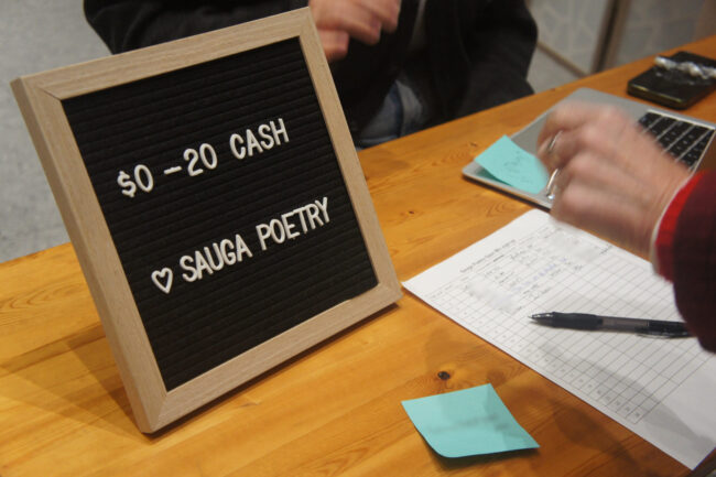 A sign reading "$0-20 cash" and "Sauga Poetry"