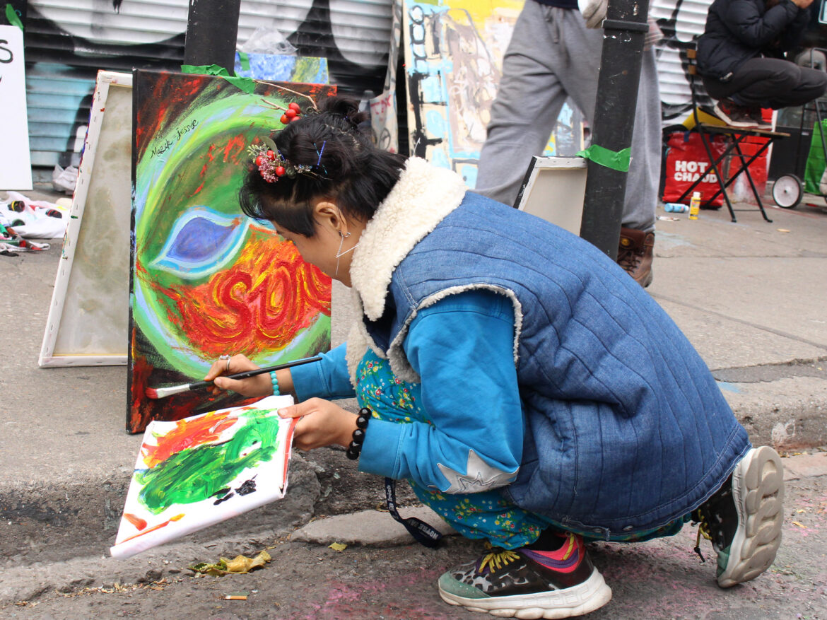 "Magic Finger Jessie" is pictured painting with colors of red, green and blue on the streets of Kensington Market.