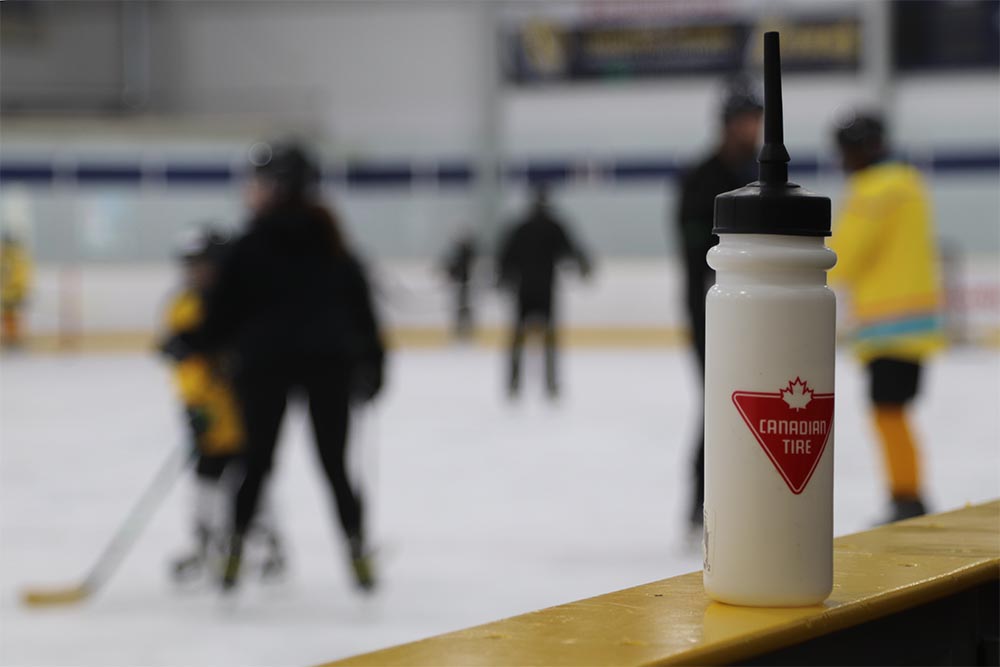 A Canadian Tire sports water bottle is pictured on top of the boards in a hockey rink.