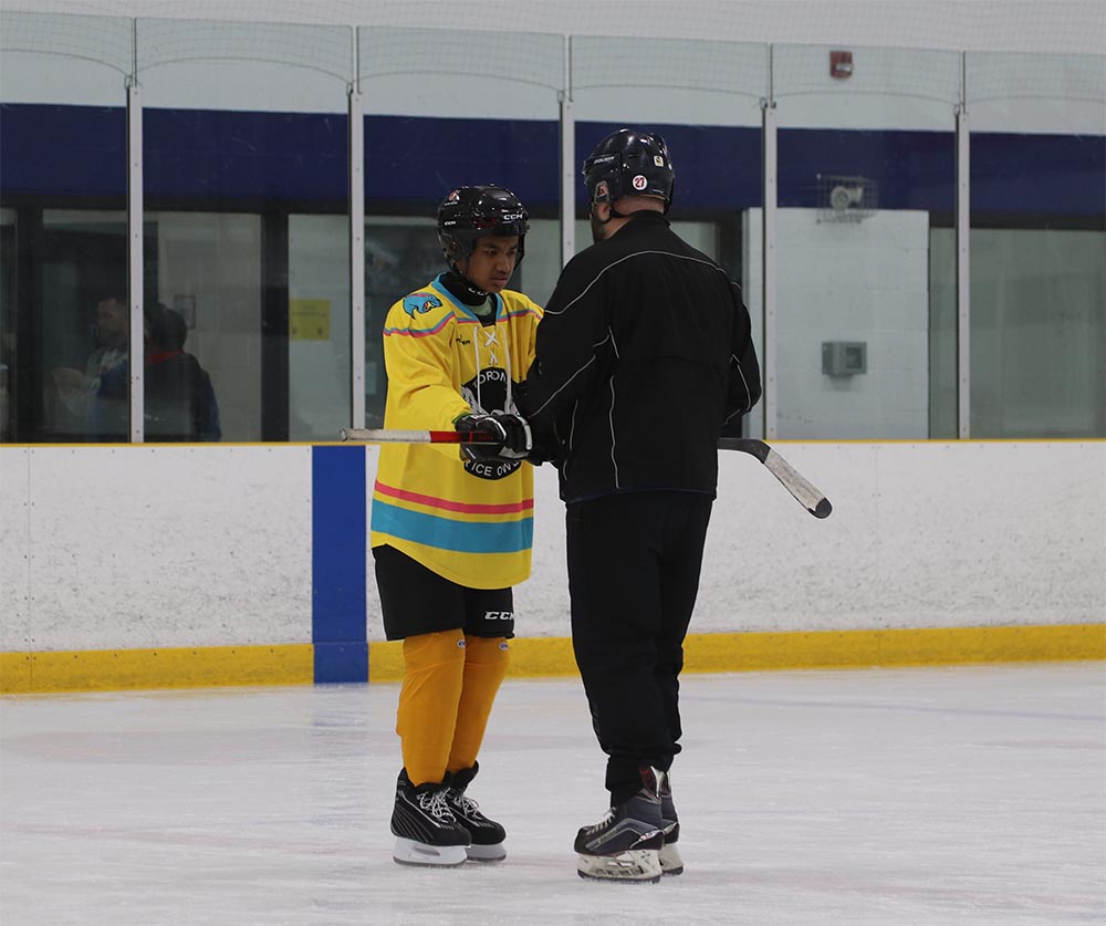 An instructor guides a partially sighted youth on the ice during a Toronto Jr. Ice Owls practice.