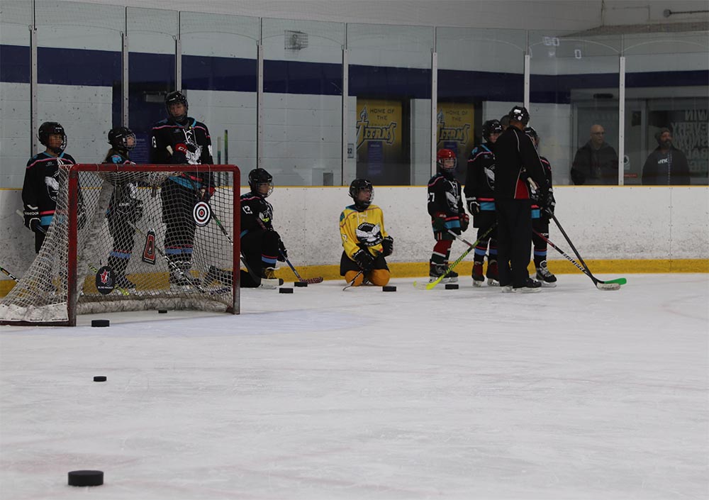 Toronto Jr. Ice Owls players surround a hockey net during practice.