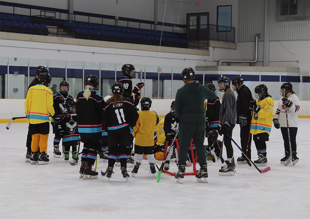 Toronto Jr. Ice Owls members gather around instructor Luca DeMontis on the ice.