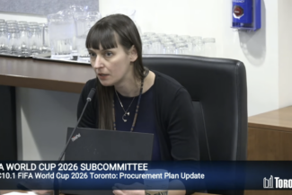 A woman speaks with a laptop in front of her during a FIFA World Cup 2026 Subcommittee session.