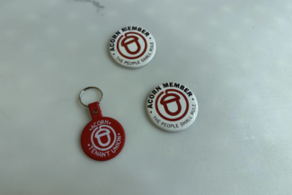 Red and white ACORN badges with the text "ACORN MEMBER" and "THE PEOPLE SHALL RULE" and a keychain with the text "ACORN TENANT UNION"